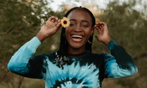 woman holds a flower in her hair in a park