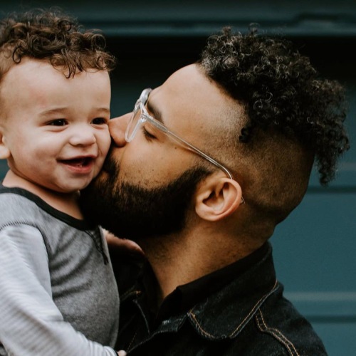 father holds and kisses his toddler son