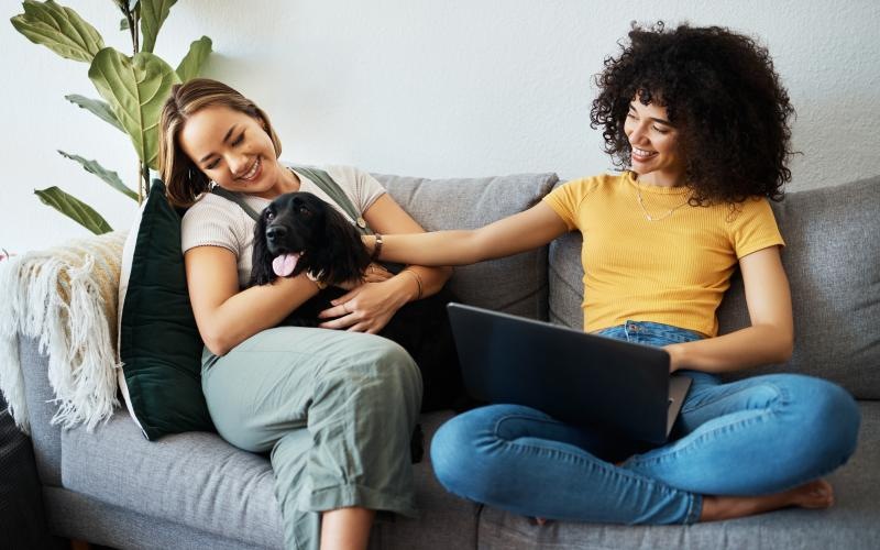 a couple of women sitting on a couch with a dog