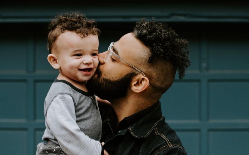 A perfect fit for the whole family father holds and kisses his toddler son